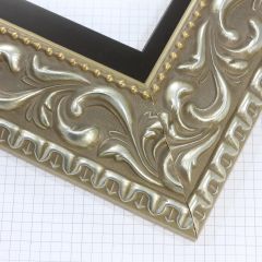 A large, reverse curve profile frame with an intricate leaf design bordered by a geometric outer edge and beaded inner lip.  A dark Silver base with foil patina for added depth on the topmost points of the design. Strong, solid wood construction.

3.25 " witdth: ideal for large and oversize (extra large) images.